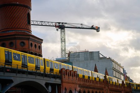 Gelber Zug fährt über historische rote Backsteinbrücke in Berlin
