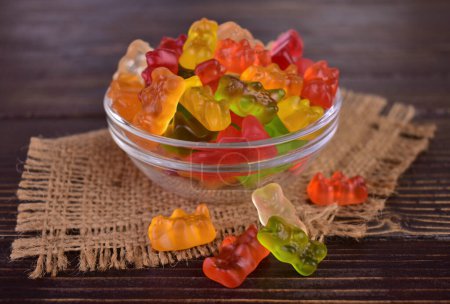 Photo for Multicolored jelly bears in a glass bowl on a dark wooden background. - Royalty Free Image