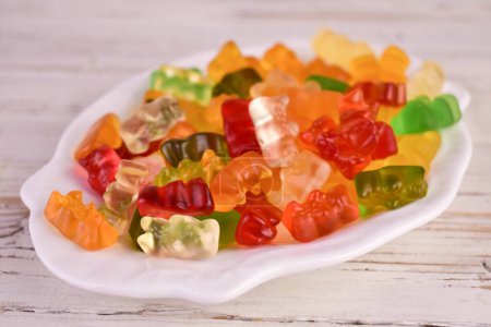 Photo for Lots of multi-colored jelly bears on a white plate. Close-up. - Royalty Free Image