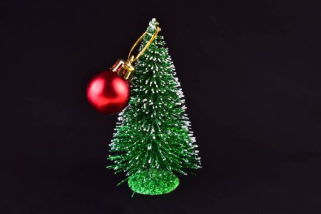 Photo for Small Christmas tree with a red ball on a black wooden background. - Royalty Free Image