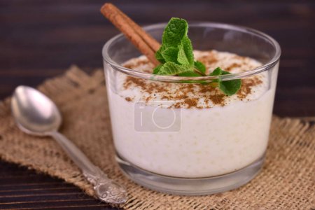 Rice pudding with cinnamon in a glass on a dark wooden background.Close-up.
