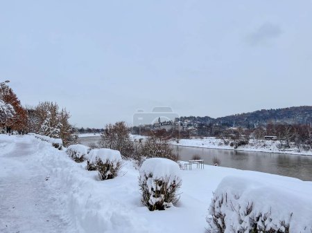 Photo for Snow-covered bench overlooking the embankment and the city under lots of snow in Przemysl, Poland made in day light - Royalty Free Image