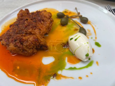 Buttermilk fried chicken and capers on white plate with honey butter 