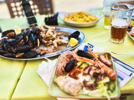 Fischteller mit Muscheln, Tintenfisch, Tintenfisch und Pommes in einem Café in Marsaxlokk, Malta
