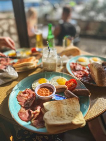 Traditionelles Frühstück mit Spiegeleiern, Speck, Würstchen und Tomatensauce auf Malta