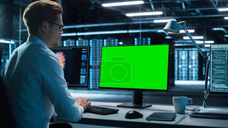 Photo for Data Center: Male Office Worker Using Computer with Green Screen Mock Up in Surveillance Center in a Monitoring Office. Specialist Works in Front of Chroma Key Display. - Royalty Free Image