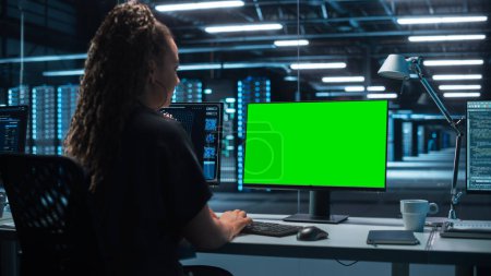 Téléchargez les photos : Ingénieur logiciel féminin travaillant dans un bureau de surveillance moderne avec écran vert maquillé sur un ordinateur. Salle de surveillance Big Data Scientifique et gestionnaire assis devant l'écran. - en image libre de droit