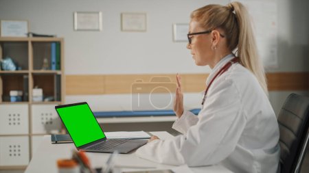 Téléchargez les photos : Consultation médicale en ligne du médecin : une femme médecin caucasienne fait une conférence téléphonique vidéo sur un ordinateur portable avec écran vert. Un professionnel de la santé donne des conseils, explique les résultats des tests. - en image libre de droit