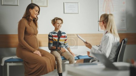 Photo for Female Family Doctor Talking with Young Pregnant Woman and Her Teenage Boy with Broken Arm During Consultation in a Health Clinic. Experienced Physician in Lab Coat in Hospital Office. - Royalty Free Image