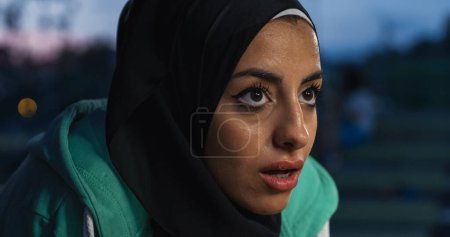 Téléchargez les photos : Portrait rapproché de la femme arabe musulmane courant en plein air le soir. Sueurs et femmes fatiguées avec un hijab se sentant motivées, travaillant et s'entraînant la nuit - en image libre de droit