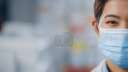 Photo for Beautiful Female Specialist Wearing Face Mask Looks Confidently at the Camera. Asian Woman with Amazing Dark Eyes and Black Hair Looks Ahead to the Bright Future. Half of the Face Concept Shot - Royalty Free Image