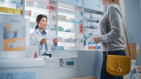 Photo for Pharmacy Drugstore Checkout Counter: Customer gives Prescription to Professional Female Pharmacist who Finds Medicine Package, Explains how to Use it. - Royalty Free Image