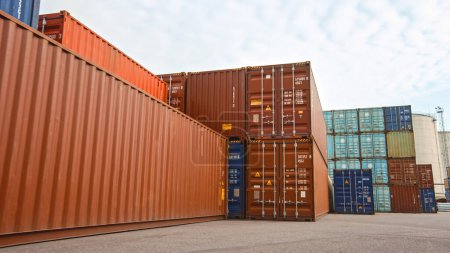 Photo for Low Angle Shot of an Industrial Terminal Location in a Shipyard Logistics Operations Center with Red and Blue Steel Shipping Cargo Containers. Daylight Cloudy Outdoors. - Royalty Free Image