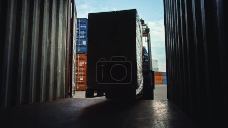 Photo for Forklift Driver Loading or Unloading a Shipping Cargo Container with a Full Pallet with Carboard Boxes in Logistics Operations Port Terminal. Shot from Inside the Container, - Royalty Free Image