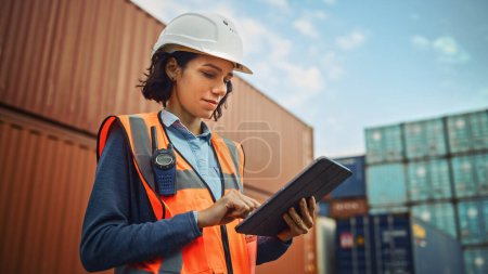 Photo for Smiling Portrait of a Beautiful Latin Female Industrial Engineer in White Hard Hat, High-Visibility Vest Working on Tablet Computer. Inspector or Safety Supervisor in Container Terminal. - Royalty Free Image