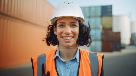 Photo for Smiling Portrait of a Beautiful Hispanic Female Industrial Engineer in White Hard Hat, Safety Vest and with Two-Way Radio Working in Logistics Center. Inspector or Supervisor in Container Terminal. - Royalty Free Image