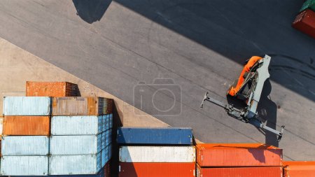 Téléchargez les photos : Vue aérienne du haut vers le bas d'un conteneur transportant un grand conteneur de fret rouge dans un terminal de chantier naval. Le conducteur de la machine charge la caisse dans le dépôt du centre logistique. - en image libre de droit