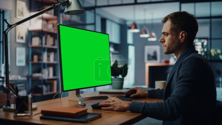 Photo for Handsome Caucasian Specialist Working on Desktop Computer with Green Screen Mock Up Display at Home Living Room. Freelance Man Chatting to Clients Over the Internet on Social Networks. - Royalty Free Image