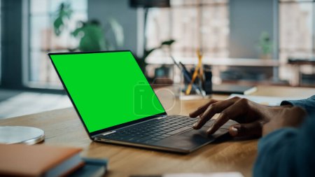 Photo for Close Up on Hands of Black African American Specialist Working on Laptop Computer with Green Screen Mock Up Display at Home Living Room. Freelance Man Chatting to Clients Over the Internet. - Royalty Free Image