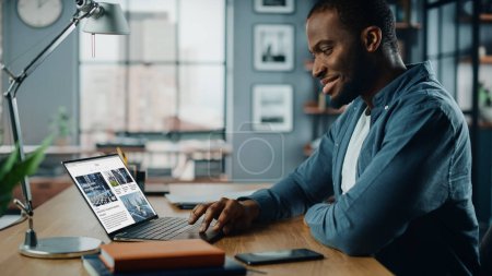 Photo for Handsome Black African American Specialist Working on Laptop Computer in Creative Home Living Room. Freelance Male is Reading News for Financial Market Analysis and Report for Clients and Employer. - Royalty Free Image
