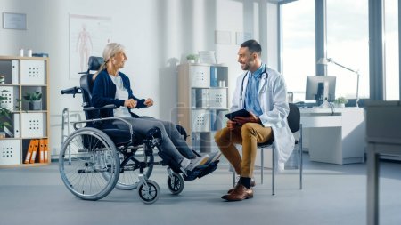 Téléchargez les photos : Physiothérapie hospitalière : Une femme âgée forte en fauteuil roulant, parle à un physiothérapeute de réadaptation amicale Les médecins donnent des conseils, planifient un traitement de réadaptation pour un patient handicapé déterminé - en image libre de droit