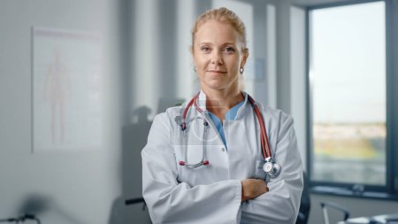 Téléchargez les photos : Gros plan Portrait d'une belle femme caucasienne médecin professionnel debout dans son bureau de clinique de santé. Succès, Médecin héros confiant regarde la caméra, Sourires à l'hôpital - en image libre de droit