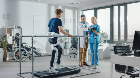 Téléchargez les photos : Physiothérapie hospitalière moderne : Patient avec blessures marche sur tapis roulant portant un exosquelette robotique avancé. Physiothérapie Réadaptation Scientifiques, ingénieurs, médecins Aide aux personnes handicapées - en image libre de droit