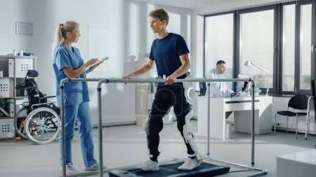 Photo for Modern Hospital Physical Therapy: Doctor Uses Tablet Computer, Helps Disabled Patient with Injury Walk on Treadmill Wearing Advanced Robotic Exoskeleton Legs. Physiotherapy Rehabilitation Technology - Royalty Free Image