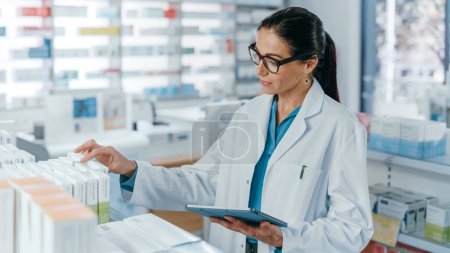 Photo for Pharmacy Drugstore: Beautiful Caucasian Pharmacist Uses Digital Tablet Computer, Checks Inventory of Medicine, Drugs, Vitamins, Health Care Products on a Shelf. Professional Pharmacist in Pharma Store - Royalty Free Image