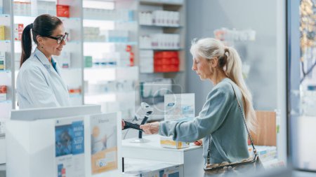 Photo for Pharmacy Drugstore Checkout Counter: Professional Female Pharmacist Sells Medicine to Diverse Group of Multi-Ethnic Customers, they Pay Using Contactless Payment Credit Card to Buy Drugs, Vitamins - Royalty Free Image
