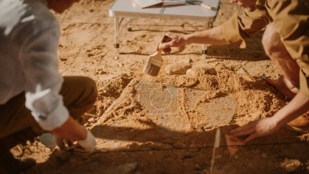 Photo for Archaeological Digging Site: Two Great Archeologists Work on Excavation Site, Carefully Cleaning, Lifting Newly Discovered Ancient Civilization Cultural Artifact, Historic Clay Tablet. Focus on Hands - Royalty Free Image