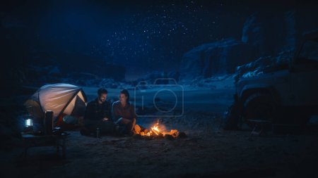 Female Traveler Sitting on Her Off Road SUV hood Watching Night Sky while Camping in the Canyon by Campfire. Traveling Woman Adventurer on Inspirational Journey Marvels at Milky Way Stars