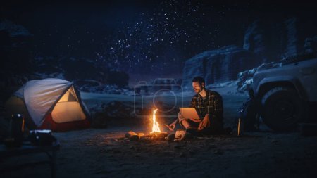 Foto de Viajera sentada en su capó todoterreno viendo el cielo nocturno mientras acampaba en el cañón junto a Campfire. Aventurera viajera en un viaje inspirador Maravillas en la Vía Láctea Estrellas - Imagen libre de derechos