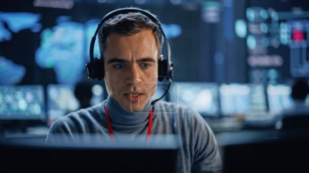 Photo for Professional IT Technical Support Specialist and Software Developer Working on Computer in Monitoring Control Room with Digital Screens. Employee Use Headphones with Mic and Talking on a Call. - Royalty Free Image