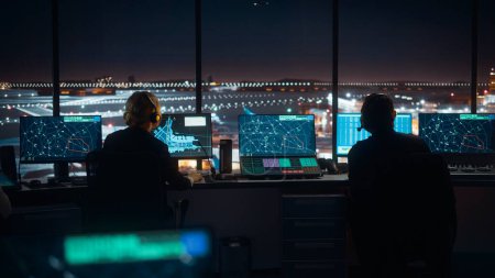 Foto de Equipo de Control de Tráfico Aéreo Diverso Trabajando en una Torre Moderna del Aeropuerto por la Noche. La sala de oficina está llena de pantallas de computadora de escritorio con pantallas de navegación, datos de radar de vuelo de avión para controladores. - Imagen libre de derechos