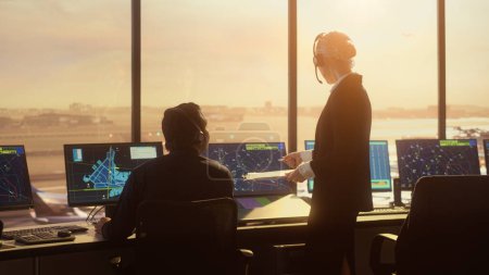 Photo for Diverse Air Traffic Control Team Working in Modern Airport Tower at Sunset. Controllers Celebrate the First Take Off of a New Commercial Aircraft with Clapping Hands in a Room Full of Computers. - Royalty Free Image