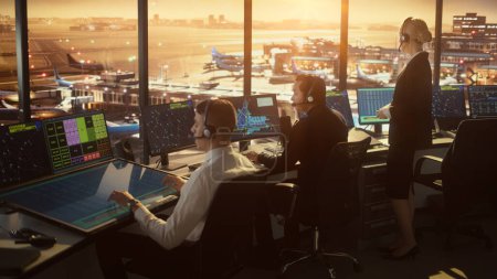 Equipo de Control de Tráfico Aéreo Diverso Trabajando en una Torre Moderna del Aeropuerto al atardecer. La sala de oficina está llena de pantallas de computadora de escritorio con pantallas de navegación, datos de radar de vuelo de avión para controladores.