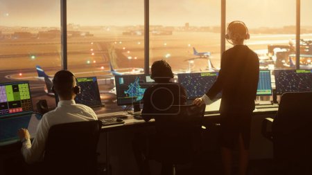 Foto de Equipo de Control de Tráfico Aéreo Diverso Trabajando en una Torre Moderna del Aeropuerto al atardecer. La sala de oficina está llena de pantallas de computadora de escritorio con pantallas de navegación, datos de radar de vuelo de avión para controladores. - Imagen libre de derechos