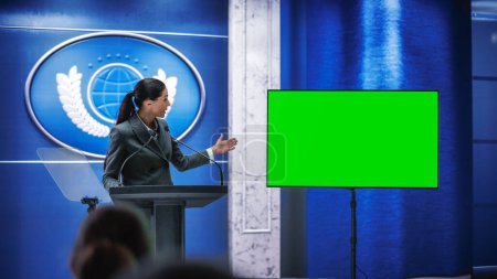 Photo for Organization Female Representative Speaking at Press Conference in Government Building with Green Screen Mock Up on Display. Press Officer Delivering a Speech at Summit. Minister in Congress. - Royalty Free Image