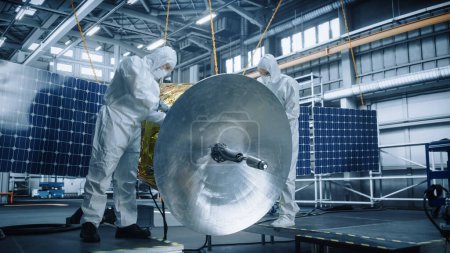 Photo for Technicians in Protective Suits Working on Satellite Construction, under Chief Engineer Control. Aerospace Agency Manufacturing Facility: Scientists Assembling Spacecraft. Space Exploration Mission - Royalty Free Image