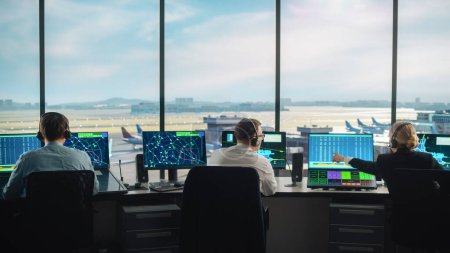 Diverse Fluglotsen arbeiten in einem modernen Flughafen-Tower. Bürozimmer ist voll von Desktop-Computer-Displays mit Navigationsbildschirmen, Flugdaten für Fluglotsen.