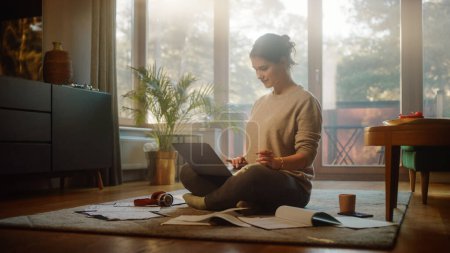 Photo for Young Woman Using Laptop at Home, Does Remote Work. Beautiful Smiling Girl Sitting on the Floor Works with Papers, Documents, Brainstorms Project with Research. Productive Work in Sunny Living Room - Royalty Free Image
