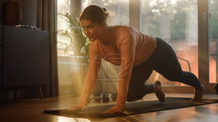 Photo for Beautiful Girl Doing Fitness at Home. Authentic Plus Size Woman Doing Workout, Mountain Climber Steps, Yoga Exercises. Healthy Fit Confident Female. Sunny Day Lights Cozy Stylish Living Room - Royalty Free Image
