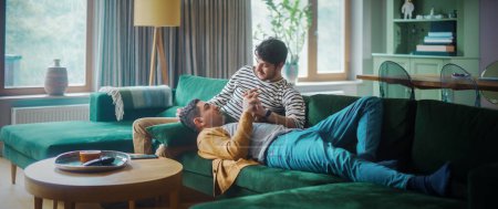 Photo for Gentle Scenes of a Stylish Young Adult Gay Couple Spend Time at Home. Two Happy Man in Love Lie Down on Sofa and Cuddle in Casual Clothes. Cute LGBT Relationship Content. - Royalty Free Image