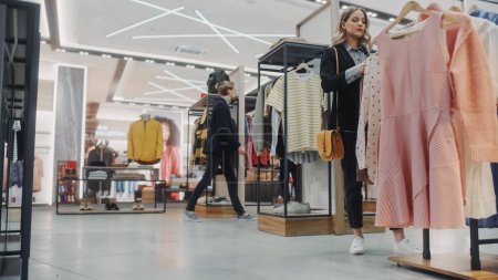 Photo for Clothing Store: Diverse Group of Costumers Shopping, Choosing, Browsing and bying Clothes and Merchandise, Retail Shopping Mall Selling Designer Brand made from Sustainable Materials. Low Angle - Royalty Free Image