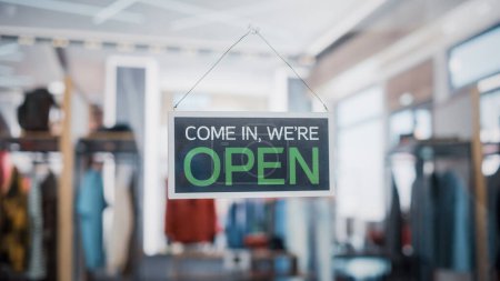 Photo for Shot of a Sign "We are Open" on a Glass Door of a Stylish Clothes Store. Blurred Background of a Shop, Supermarket, Bar or Another Company, Business. - Royalty Free Image