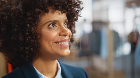 Téléchargez les photos : Portrait d'une heureuse femme noire avec des cheveux afro élégants souriant et posant pour appareil photo au magasin de vêtements. Propriétaire d'une petite entreprise dans le rôle d'une femme d'affaires ou d'un directeur des ventes diversifié. - en image libre de droit