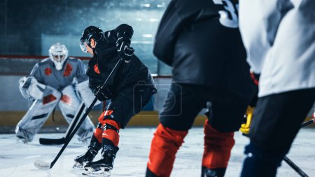 Foto de Ice Hockey Rink Arena: Profesional Forward Player Masterfully Dribbles, Breaks Defense, Ready to Hit the Puck with Stick to Score a Goal. Momento importante y de tensión. - Imagen libre de derechos