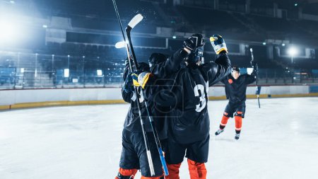 Foto de Ice Hockey Rink Arena: Forward Player Hit The Puck y anotó un gol. Equipo profesional de hockey celebra la victoria, abrazarse mutuamente. Tensión y momento deportivo emocional. - Imagen libre de derechos