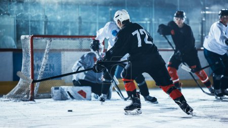 Photo for Ice Hockey Rink Arena: Professional Forward Player Breaks Defense, Hitting Puck with Stick to Score a Goal. Game Near Gate or Goal. Important and Tension Moment in Sport Full of Emotions. - Royalty Free Image